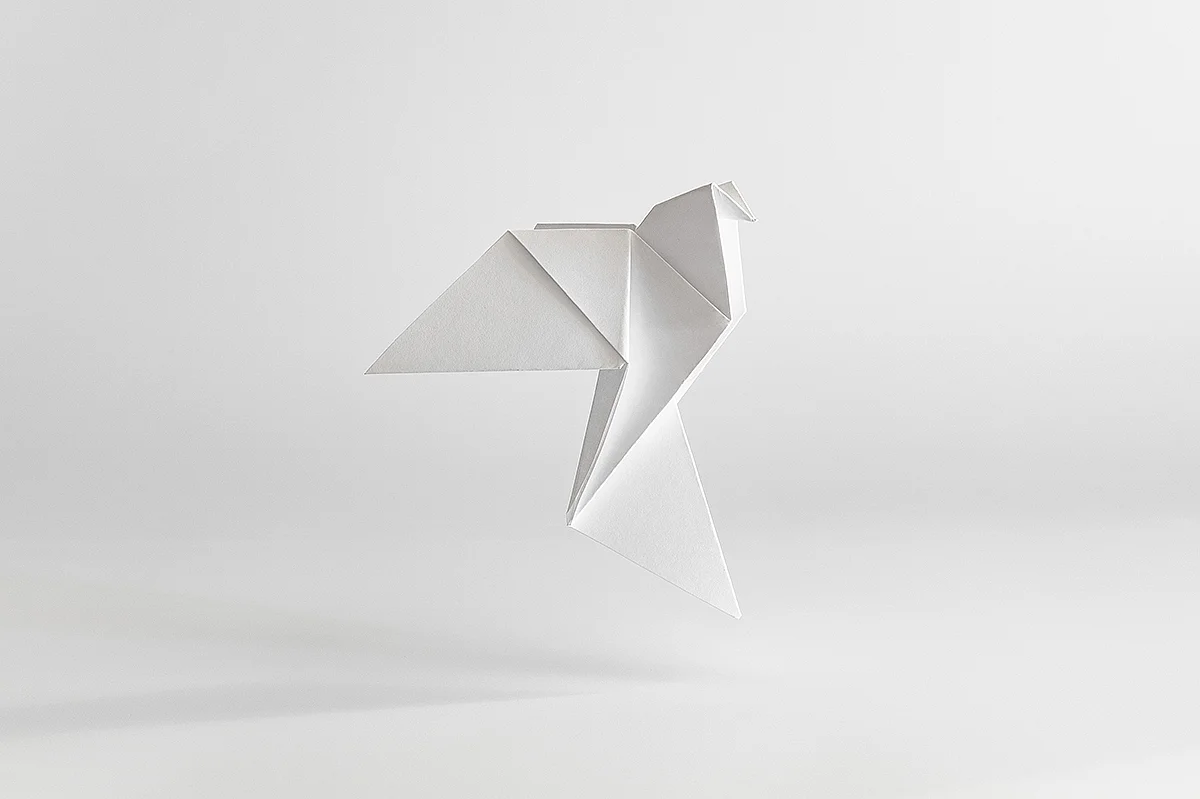 Weißer Origami-Vogel vor hellem Hintergrund.