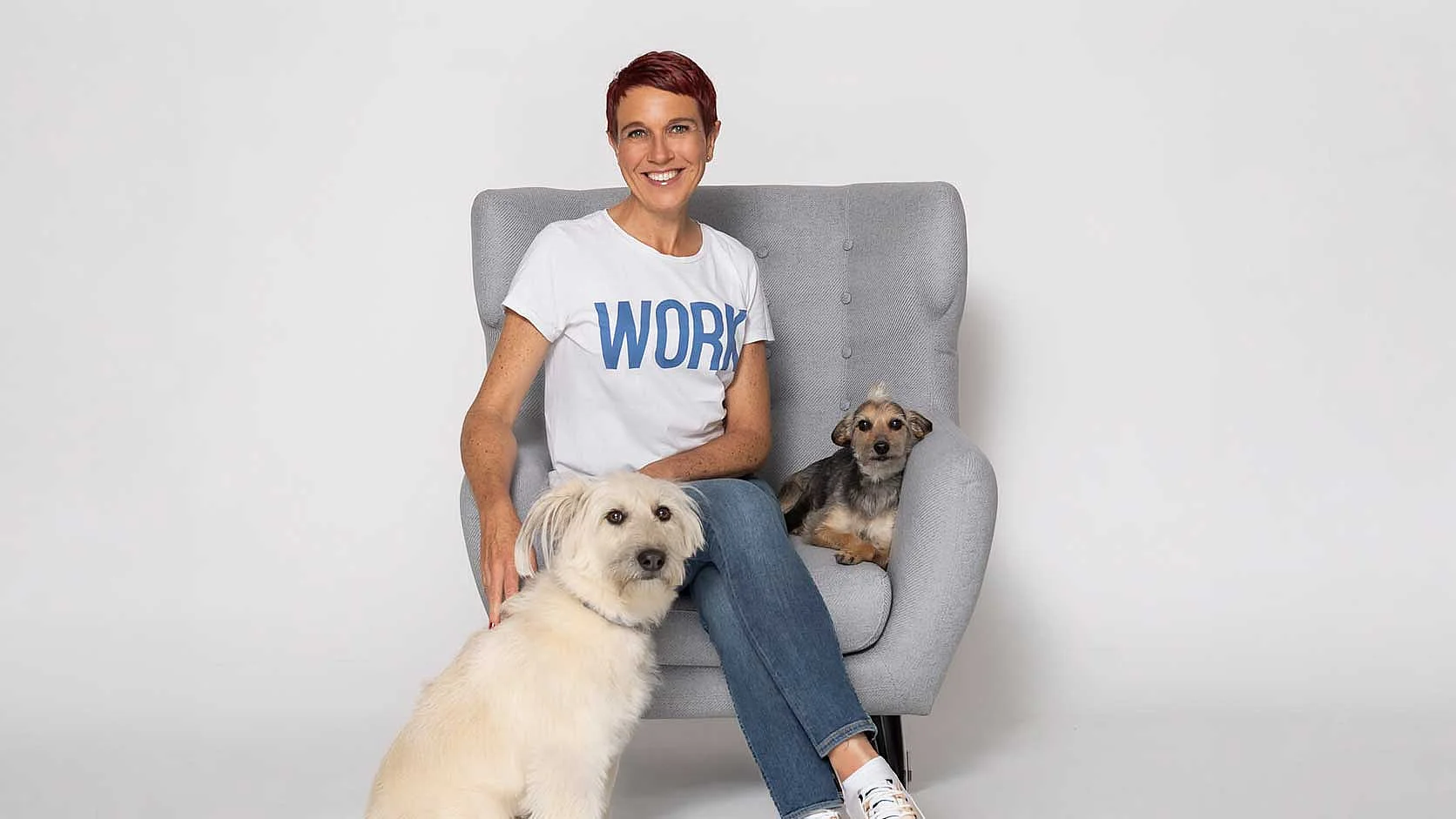 Nadine Pötz mit Hunden – FRAUPÖTZ Frau sitzt mit zwei Hunden vor hellem Hintergrund.
