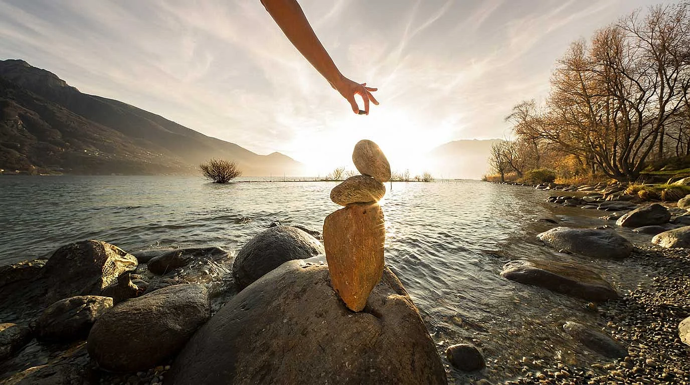 Person in einer Landschaft bei Sonnenlicht, mit ausgestreckten Armen.